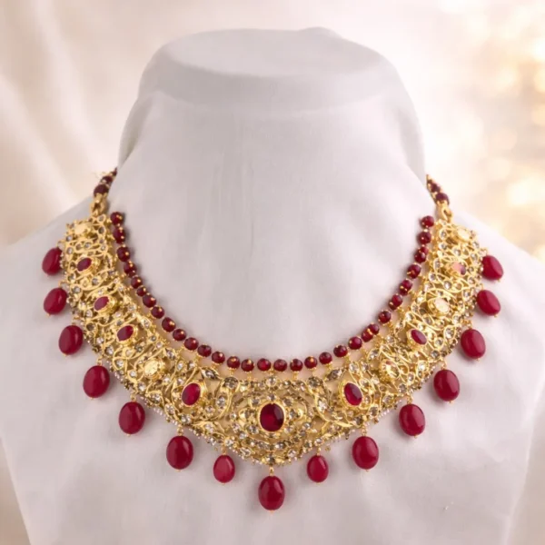 Sha Jewellers Contemporary Polki-Style Bridal Ruby Choker featuring broad gold collar with filigree and vine motifs, inner ruby bead row, inlaid oval ruby cabochons, prominent teardrop ruby fringe, and scattered CZ accents