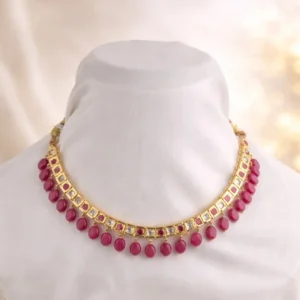 Sha Jewellers Gold Polki Ruby Choker Necklace featuring square-cut ruby beads set in gold frames along the central band with dangling round ruby drops on the bottom edge, displayed on a white mannequin against a soft beige background