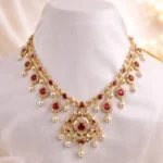 Sha Jewellers Long Pearl Drop Necklace featuring two strands of white pearls, ornate pendant with ruby-toned stones and CZ accents, cascading pearl drop fringe, and traditional adjustable sarafa cord